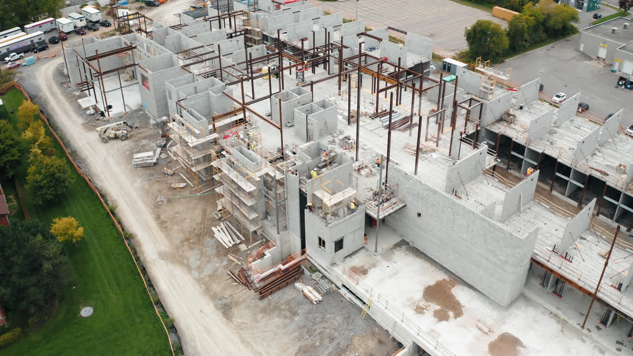 vuelo aéreo sobre un nuevo edificio comercial en desarrollo con trabajadores del sitio de construcción sindicales empleados que operan trabajos de maquinaria pesada viviendas industriales urbanas inmobiliarias 4k