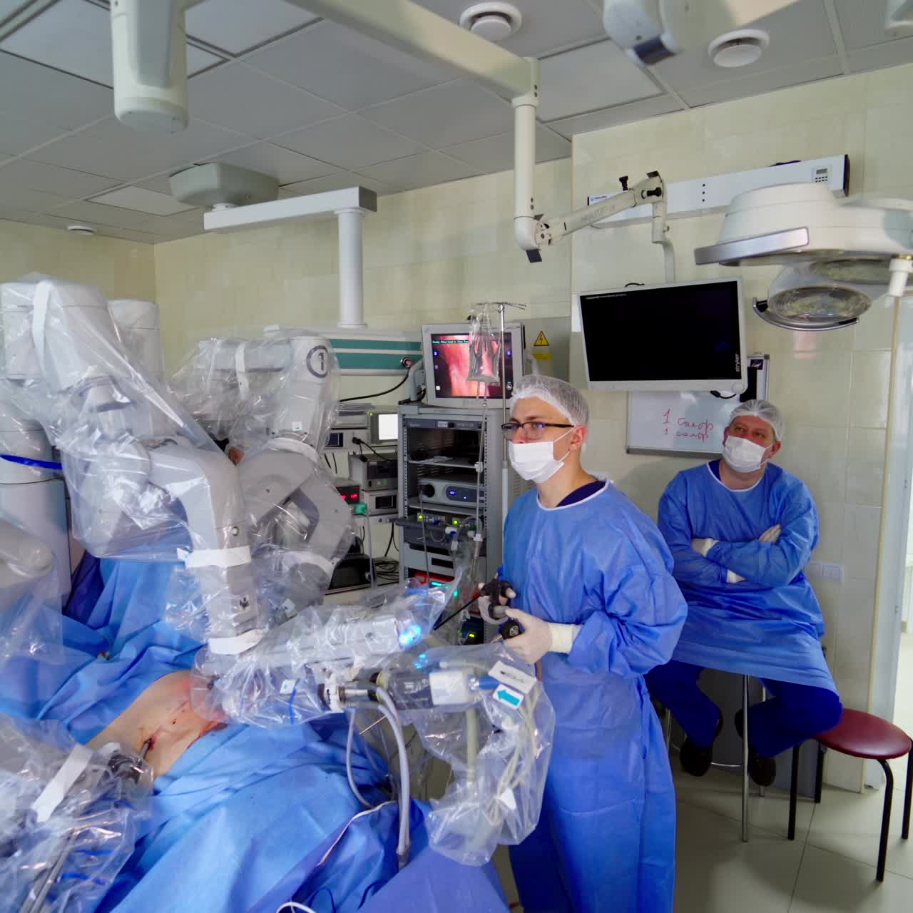 Minimally invasive robotic surgery. Robot arm performing surgical operation on patient