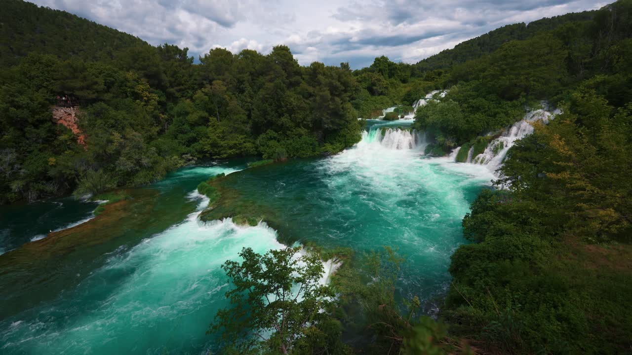 Scenic view of Krka National Park waterfalls in slow motion, dense green forest and cliffs, Croatia