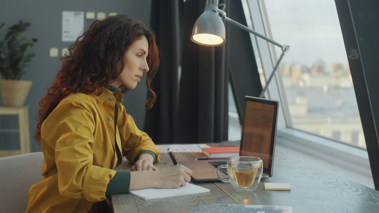 mujer de negocios trabajando en una computadora portátil y tomando notas en la oficina