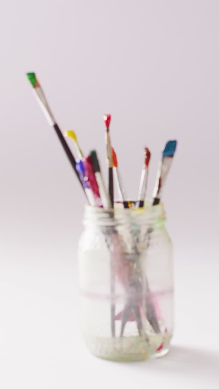 video vertical de pinceles usados en un frasco sobre un fondo blanco con espacio para copiar