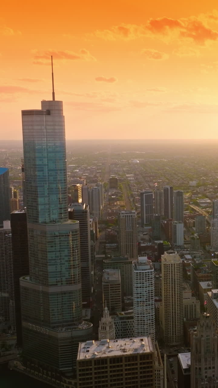 Gorgeous Chicago in the rays of setting sun. Endless city panorama at the backdrop of orange skies. Aerial view. Vertical video