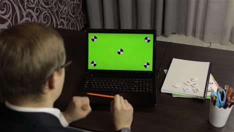 hombre haciendo una llamada de video en línea en una computadora portátil. pantalla verde. educación a distancia