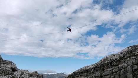 Deporte-Extremo-Del-Hombre-Saltando-En-Slackline-En-Las-Montañas-Haciendo-Trucos-Y-Divirtiéndose---Toma-Aérea-Inclinada-Hacia-Arriba