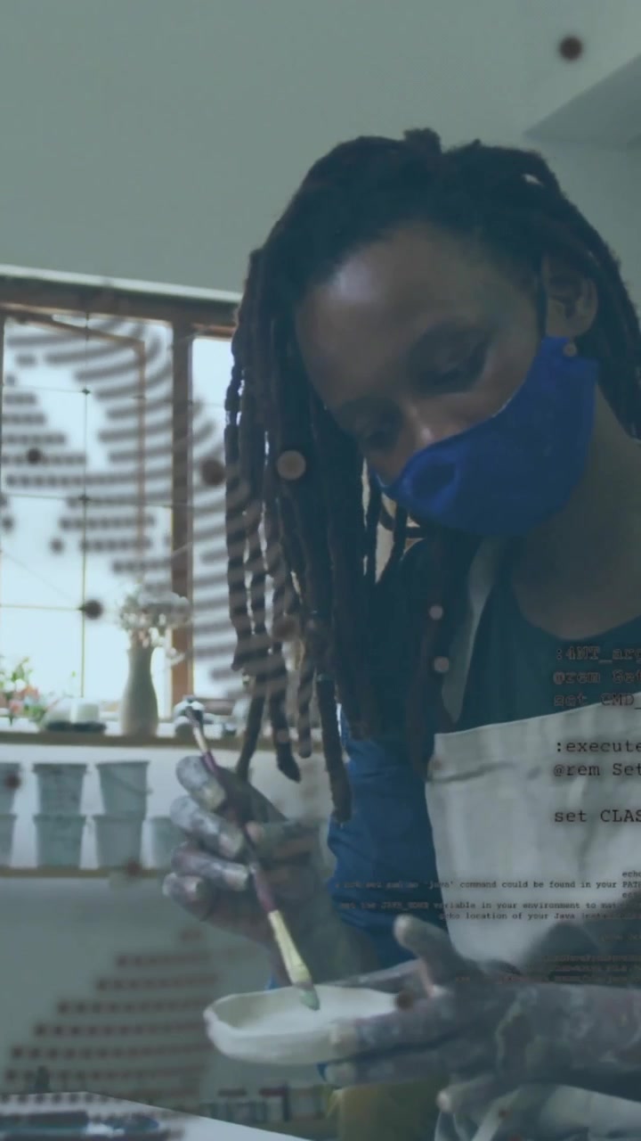 Vertical video: Pressing brush into bowl, potter rotating and brushing, inspecting glaze for decor
