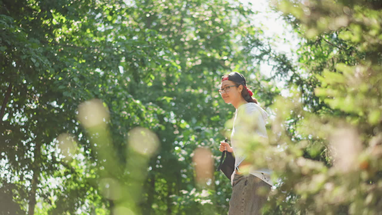 Young man stands quietly in glowing forest, Peaceful moment captured beneath sunlit pine trees during summer, Contemplative youthful figure pauses among luminous pine trees in gentle haze