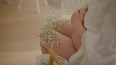 happy pregnant woman touching belly with gypsophila
