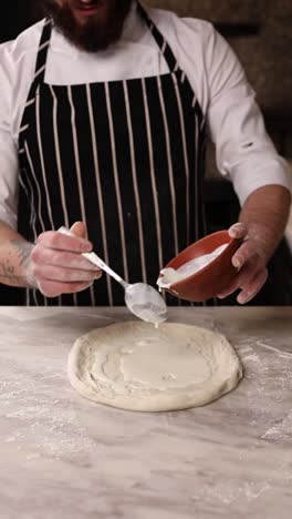 chef preparing pizza with sauce