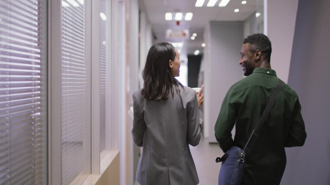 dos personas de negocios felices y diversas trabajando juntas, hablando, bebiendo café en una oficina moderna