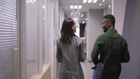 two happy diverse business people working together, talking, drinking coffee in modern office