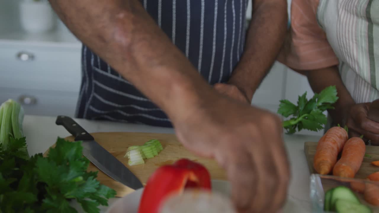 Midsection of happy african american senior couple cooking together