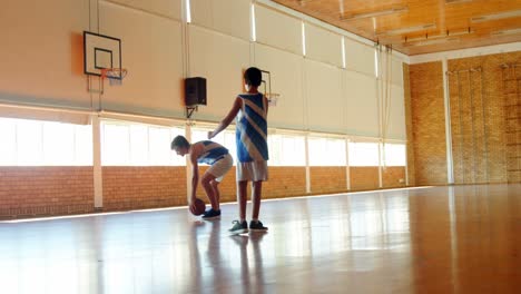 two schoolboys playing basketball in basketball court