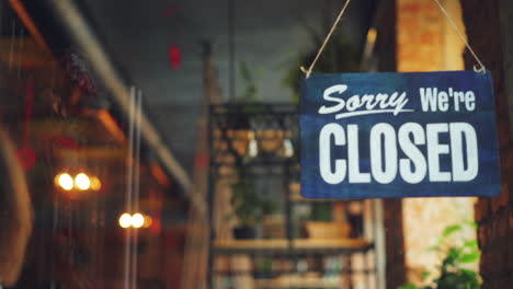 shopkeeper changing sign from open to closed