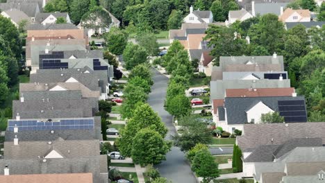 Aerial view of quiet suburban neighborhood with uniform houses, tree-lined streets and parked cars. Clean, orderly development with solar panels visible on rooftops. New Jersey, USA in summer