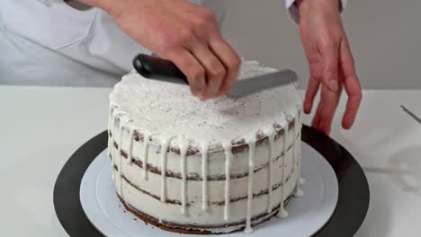 close up of a chef polishing the top of a cake by spreading the white chocolate. final steps of a cake assembly.