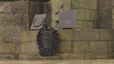 close-up of a weathered stone monument with bronze plaques and wreaths