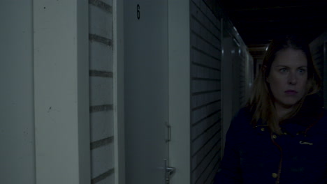 woman in dark basement noticing a dark figure in the background