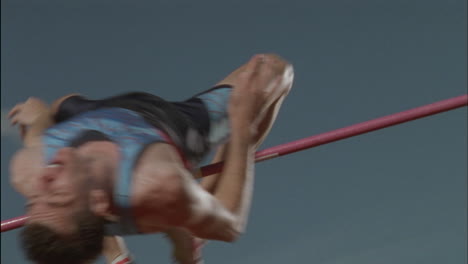 a man performs a high jump backwards over a bar