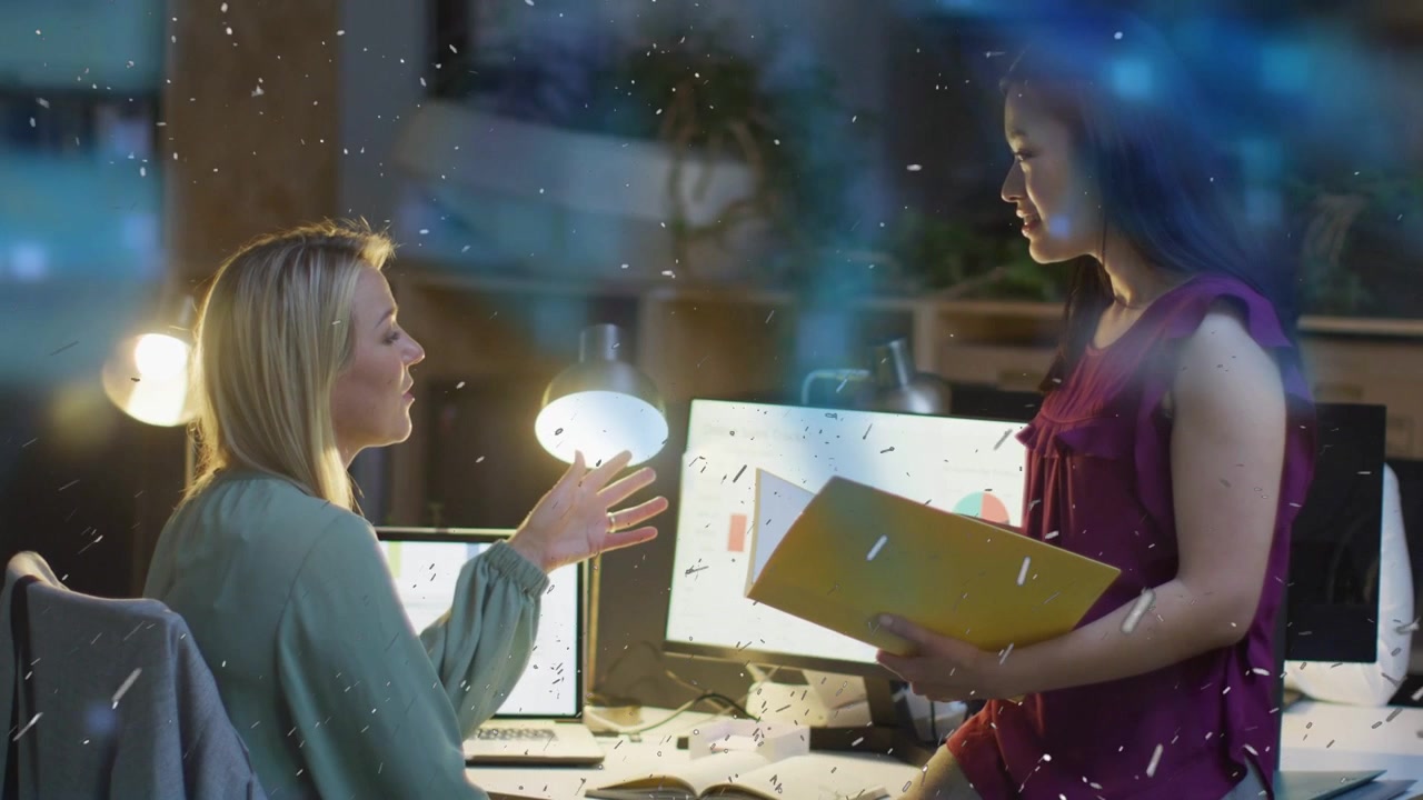 Two women reaching and pointing at screen, tilting yellow folder, overlay showing business metrics