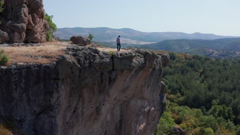 hombre camina hacia el borde de la meseta en el santuario de harman kaya en las montañas rodope, bulgaria