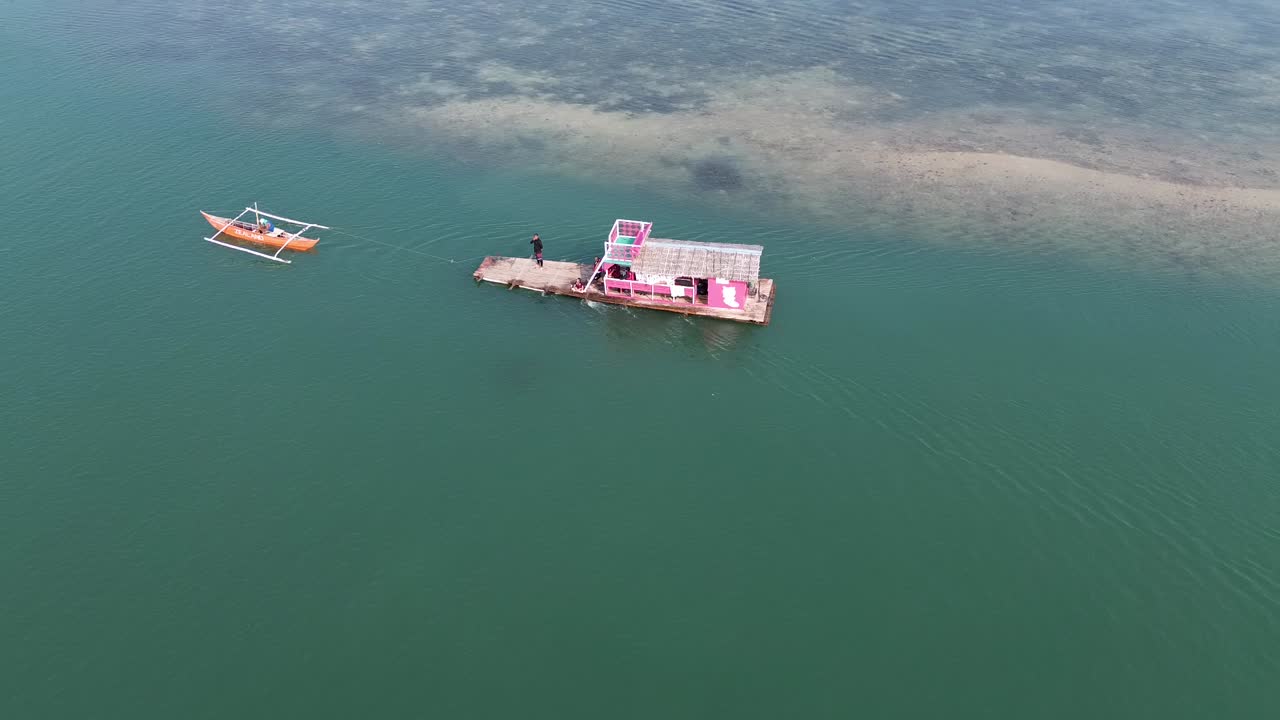 una cabaña flotante siendo tirada por un pequeño barco listo para ser atracado después de una excursión de un día en una barra de arena