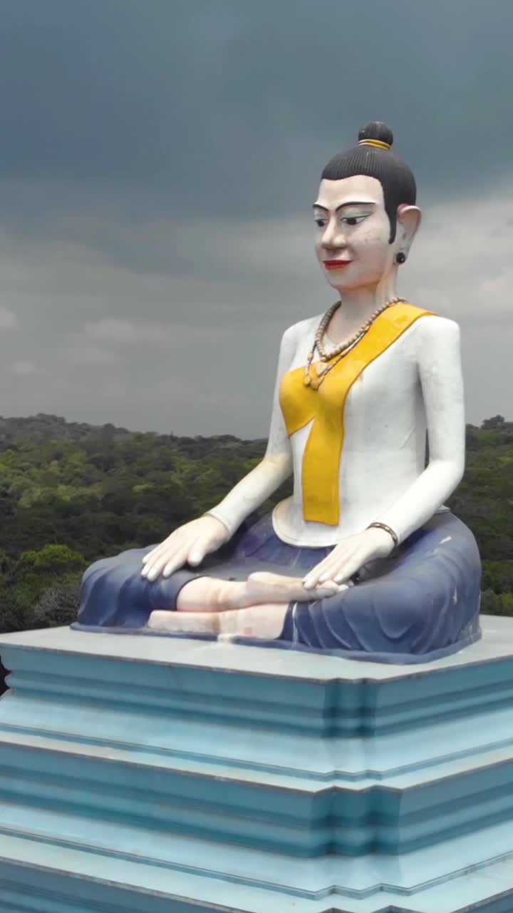 Giant statue of Lok Yeay Mao sitting in Kampot, Cambodia, a local divinity linked to the Durian fruit. Aerial, Vertical Video, Orbit Motion