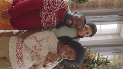 happy black family posing for camera by xmas tree at home