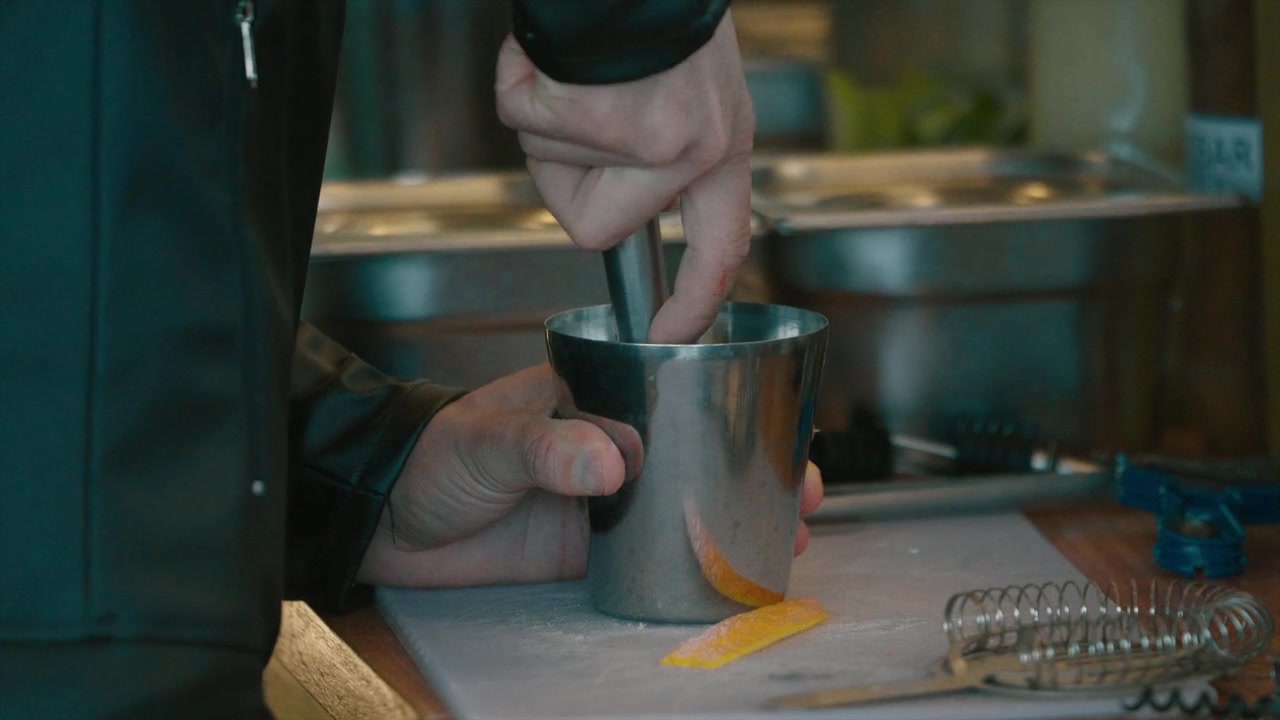 Bartender misturando ingredientes com um pilão de metal