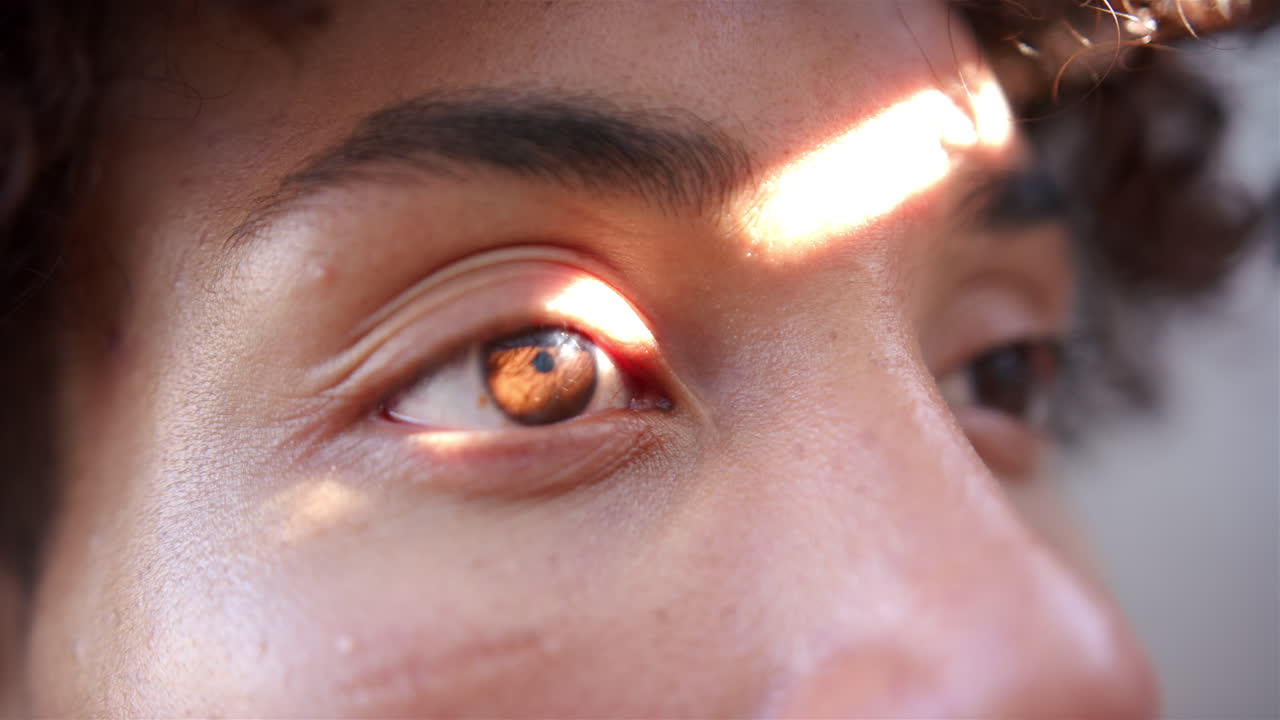 Close-up of man's eye with sunlight reflecting, showing detailed iris pattern