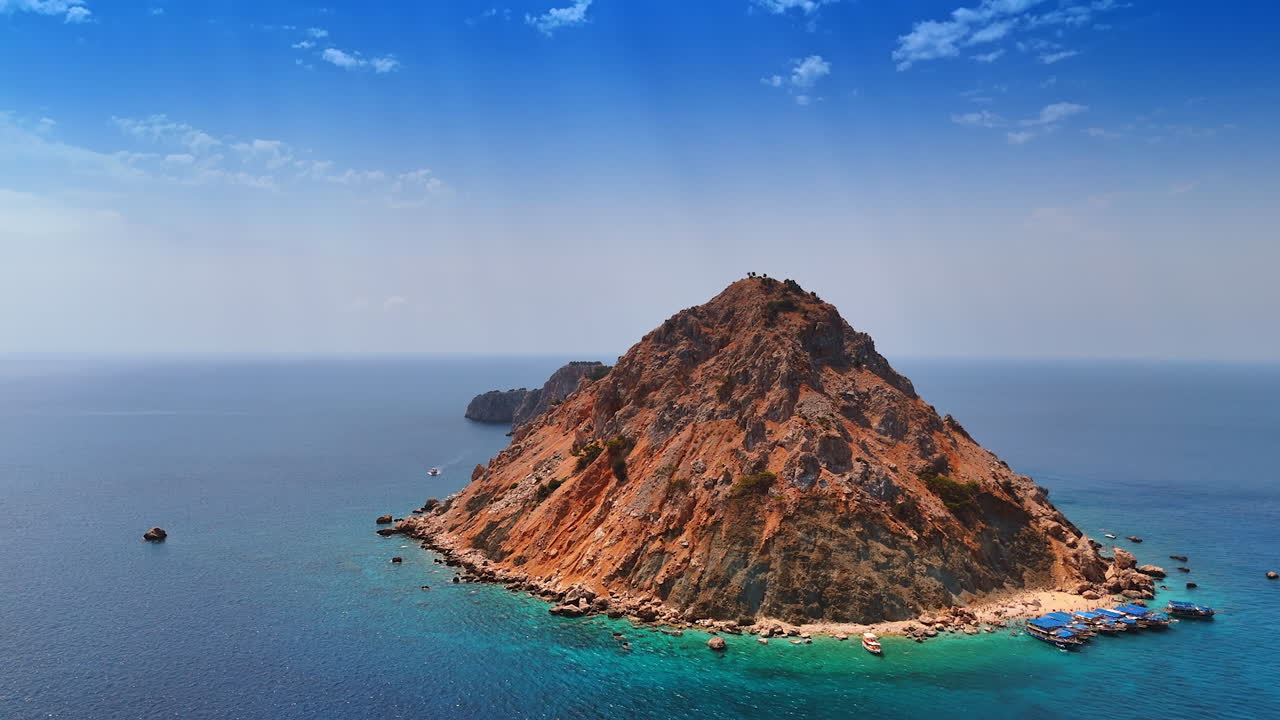 Peaceful island in calm waters. A small island with rocky peaks located in crystal-clear blue waters under a bright sky during the day