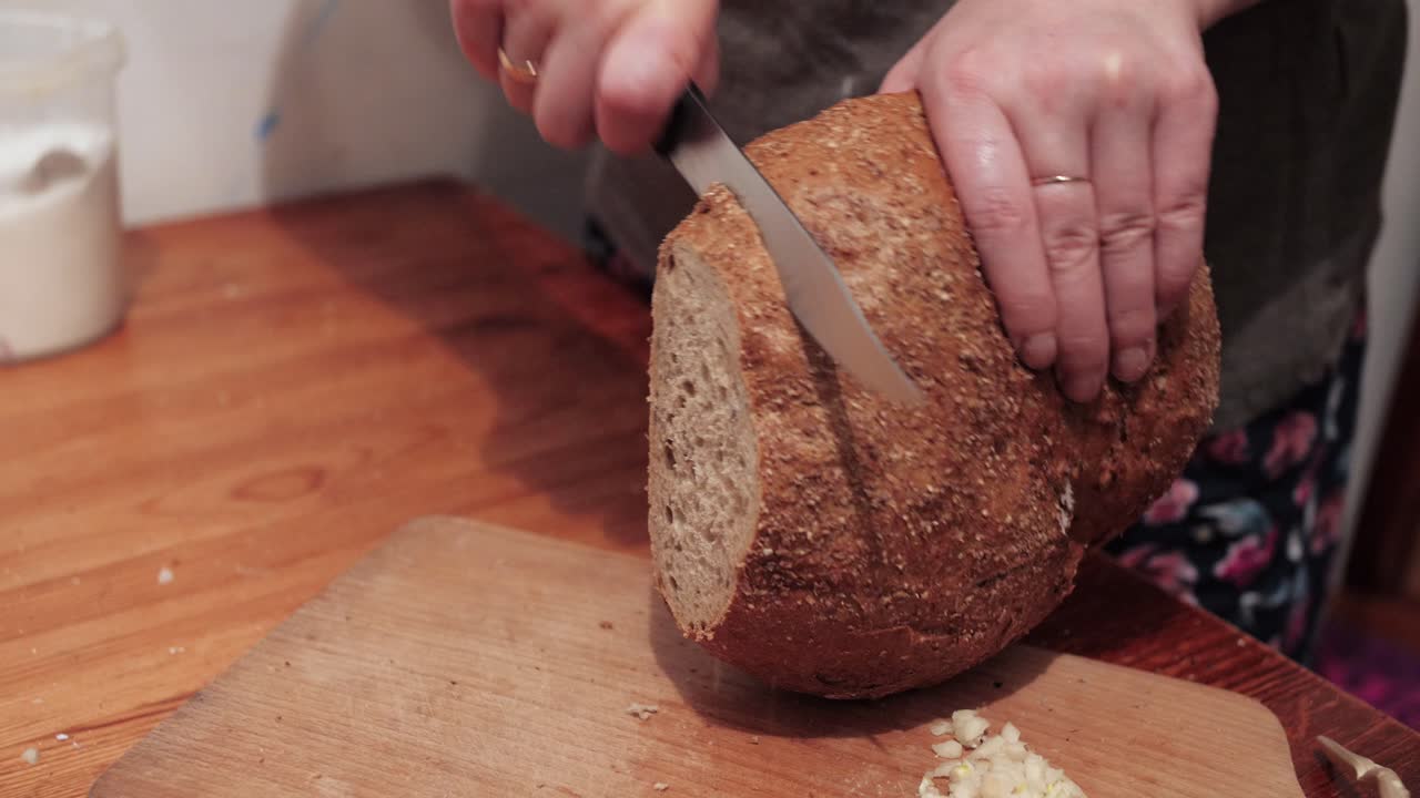 Woman's hands cut slices of round bread on a chopping board