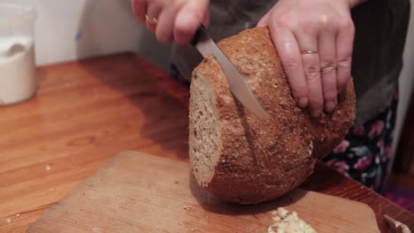 woman's hands cut slices of round bread on a chopping board