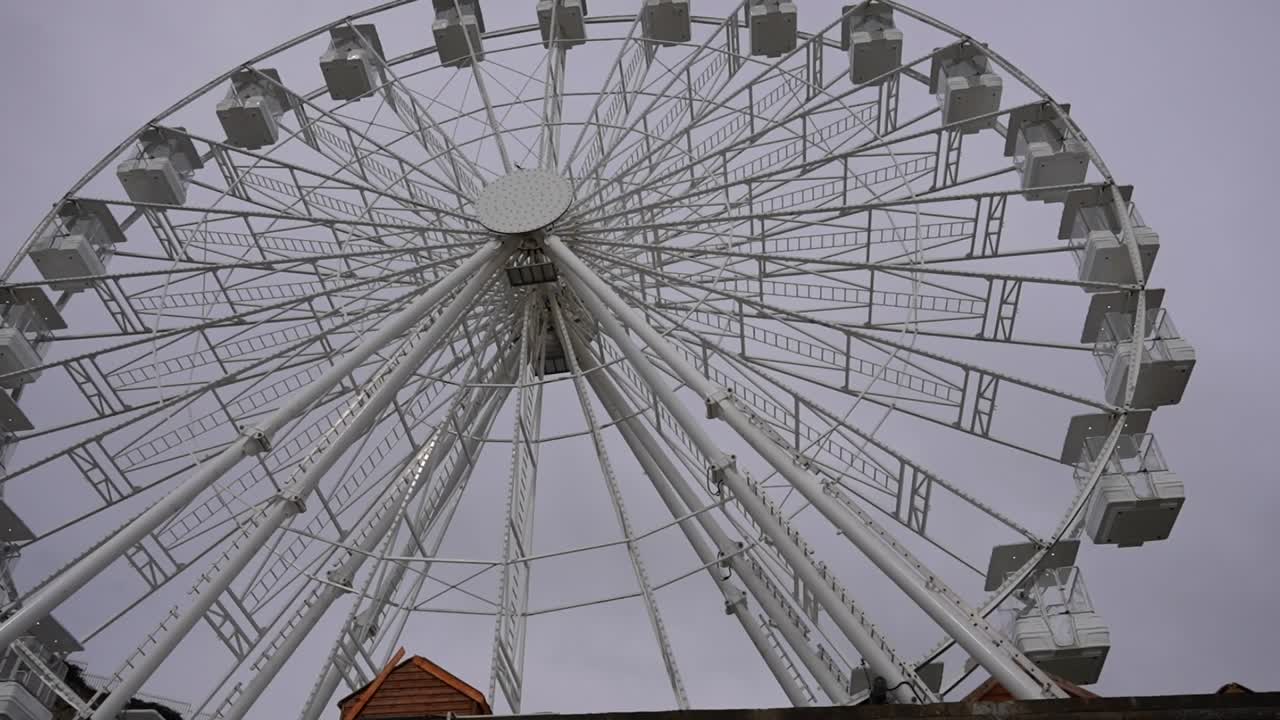 Ferris wheel spins at Mumbles Pier against a cloudy sky in Swansea Bay