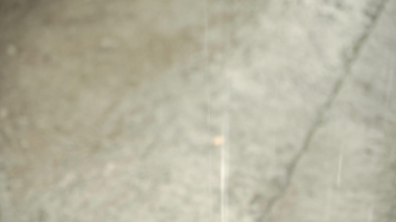 Falling raindrops on road at shallow depth of field.