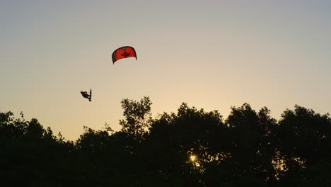 kitesurfer obtiene gran aire durante el movimiento kiteloop contra el cielo de la hora dorada