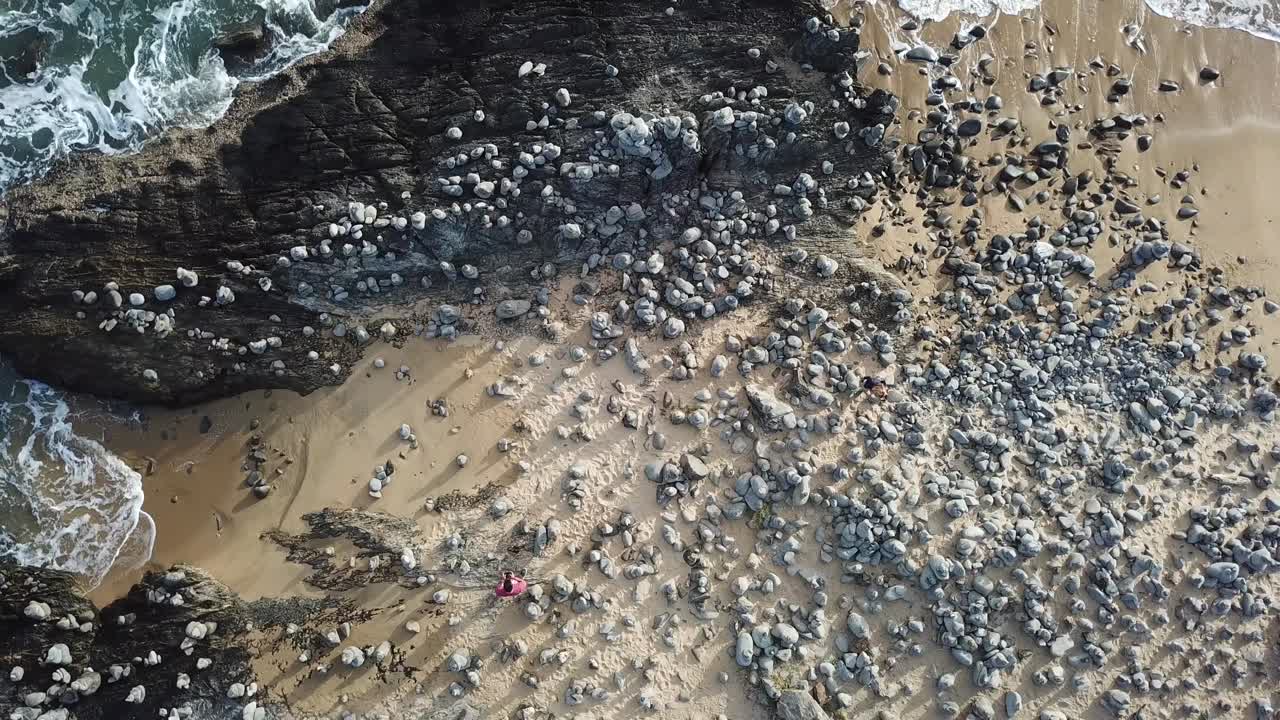 Aerea: Vista dall'alto su una spiaggia di ciottoli che si eleva lentamente per rivelare l'oceano, vicino alla Captain Cook Highway nel Far North Queensland.