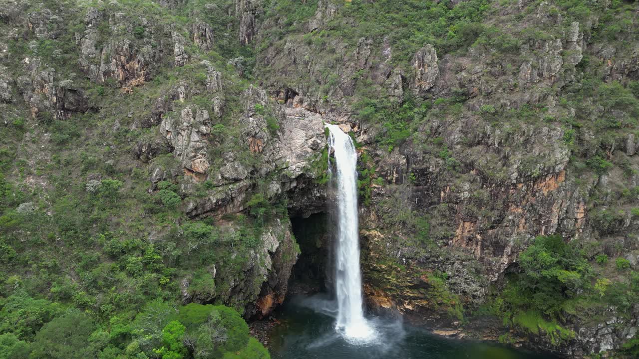 Aerial approaches misty pool below rugged Fundao waterfall in Brazil