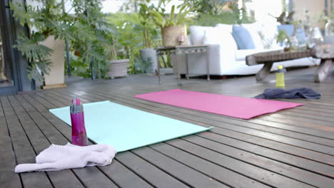 water bottle, towel and exercise mats on sunny terrace