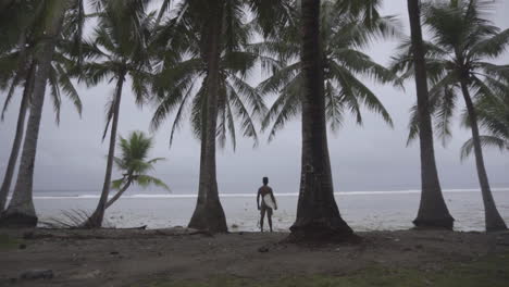 toma trasera de un surfista asiático mirando las olas