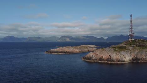 volando en la costa de henningsvaer, lofoten mirando el océano y un pequeño acantilado con montañas al fondo