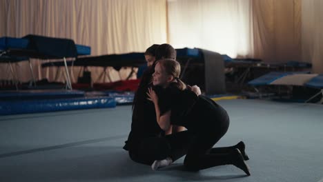 gymnastics coach and two young athletes sitting on the floor