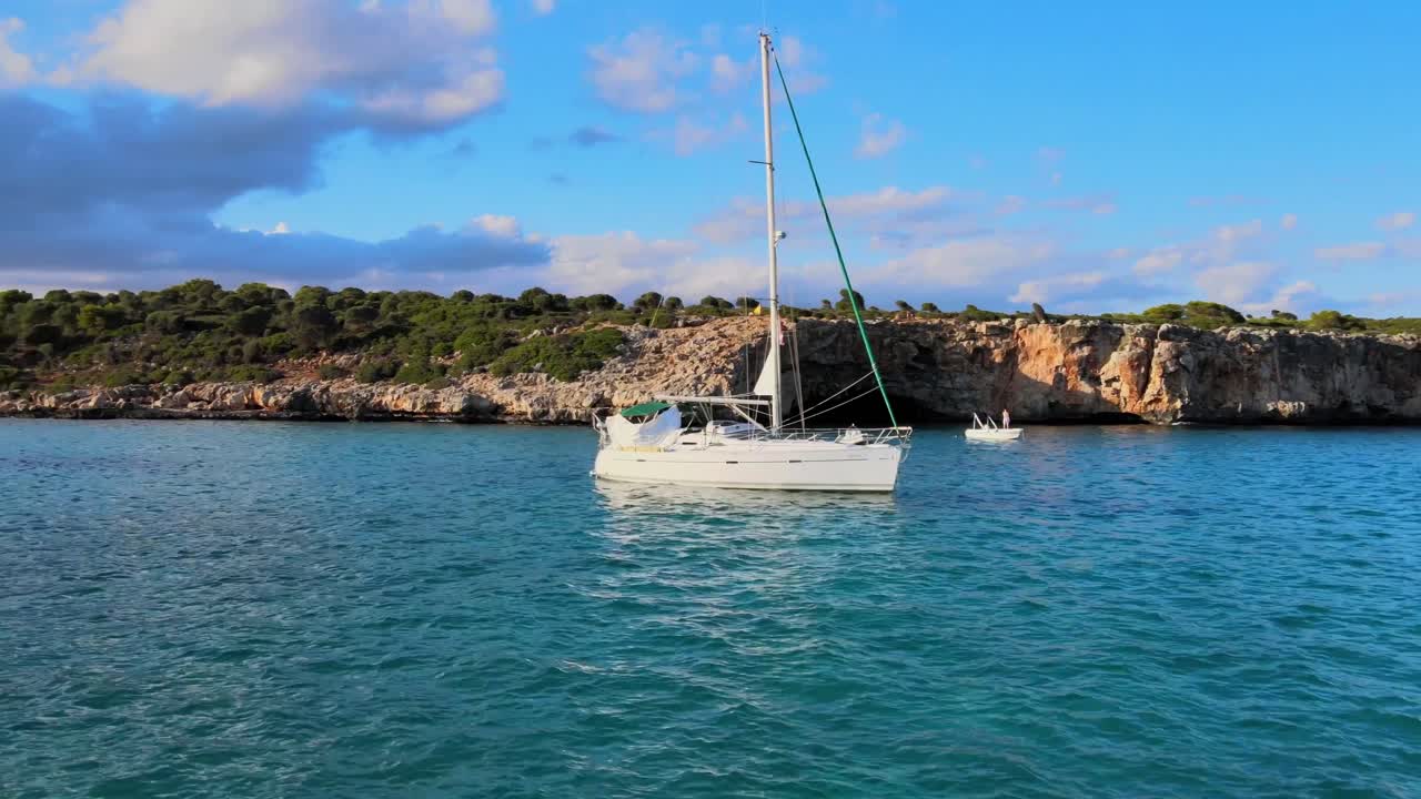 Crystal clear waters surround sailboats at Cala Varques, a stunning spot in Porto Cristo, Majorca, known for its natural beauty and serene ambiance. Perfect for a peaceful day out.
