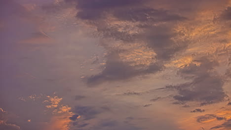 Toma-En-ángulo-Bajo-Del-Movimiento-De-Nubes-Esponjosas-Blancas-Y-Oscuras-En-El-Cielo-Azul-Durante-La-Puesta-De-Sol