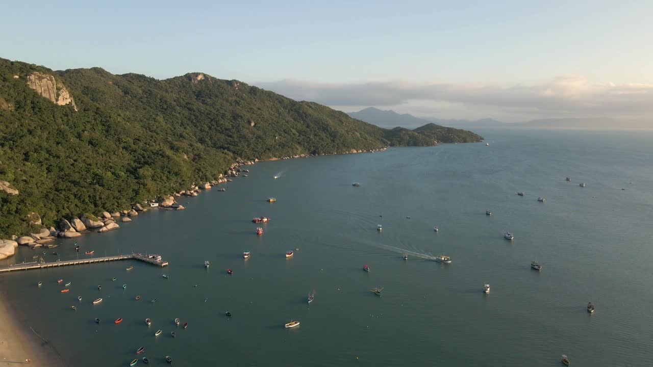pequeños barcos anclados en el mar con costa de montaña verde, aérea