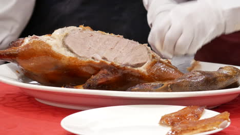 motion of chef cutting roasted duck into a plate for customer inside chinese restaurant with 4k resolution