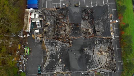 aerial view of large building with destroyed roof damaged by fire, zoom in