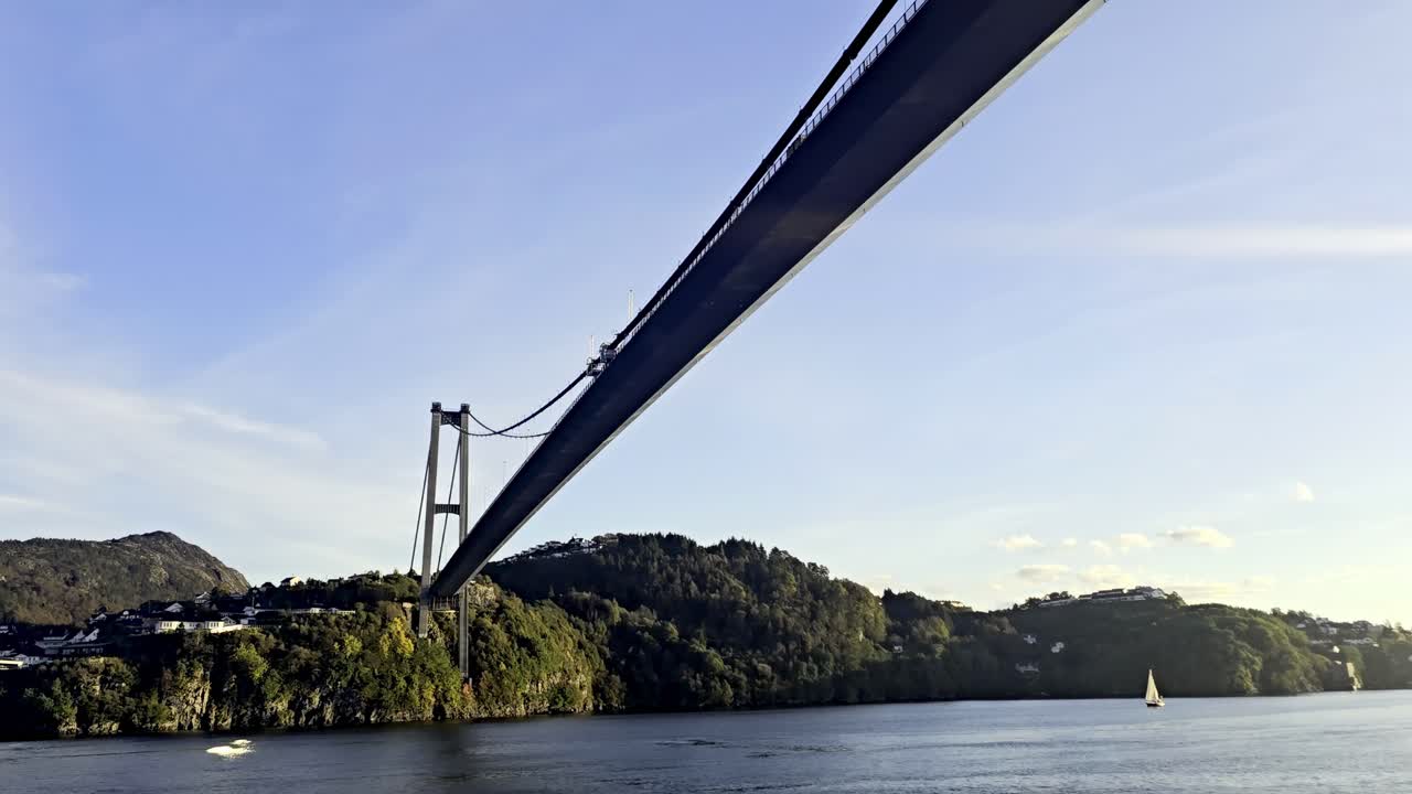 Slow upward view from boat moving under Askoy Bridge highlighting construction and maintenance focus