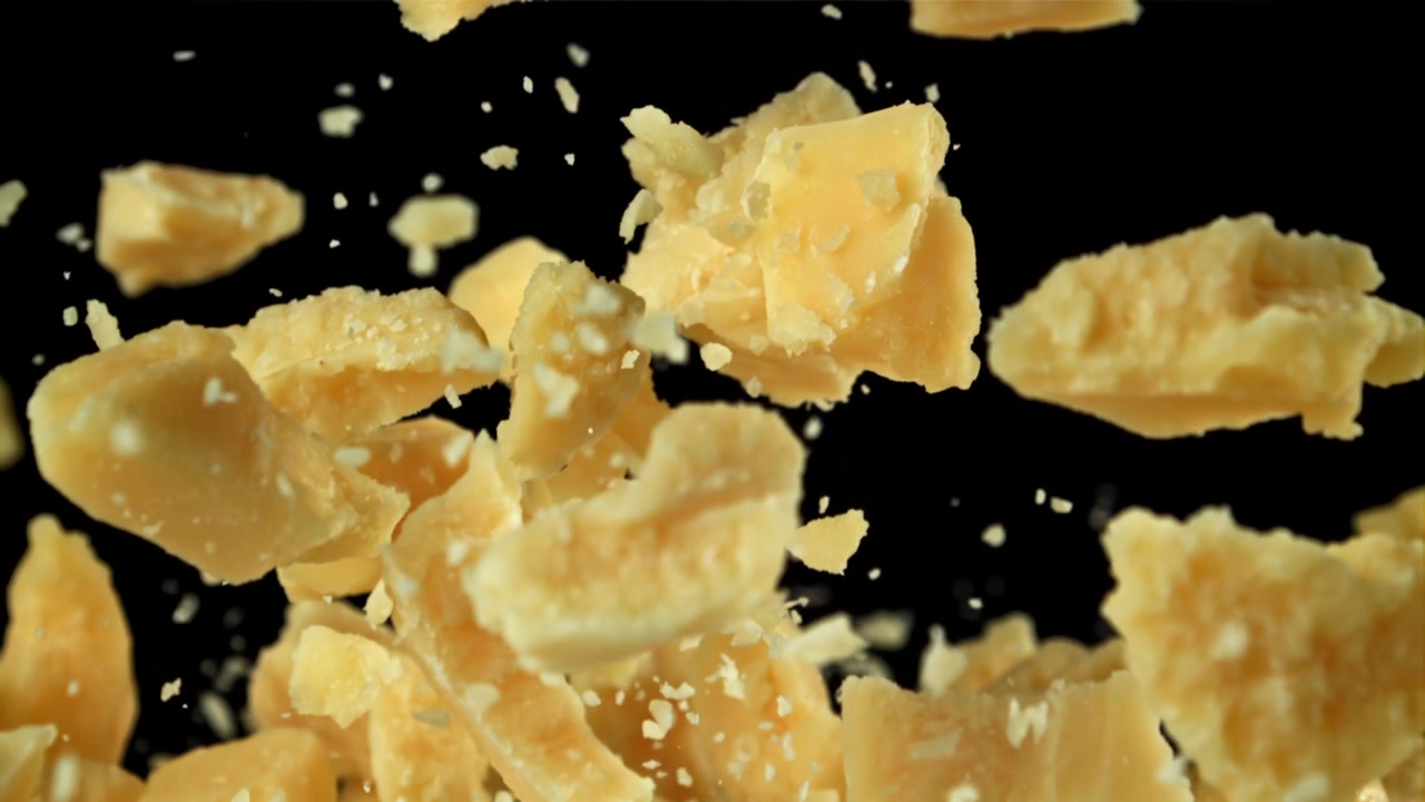 Scaglie di Parmigiano e formaggio grattugiato che volano al rallentatore.