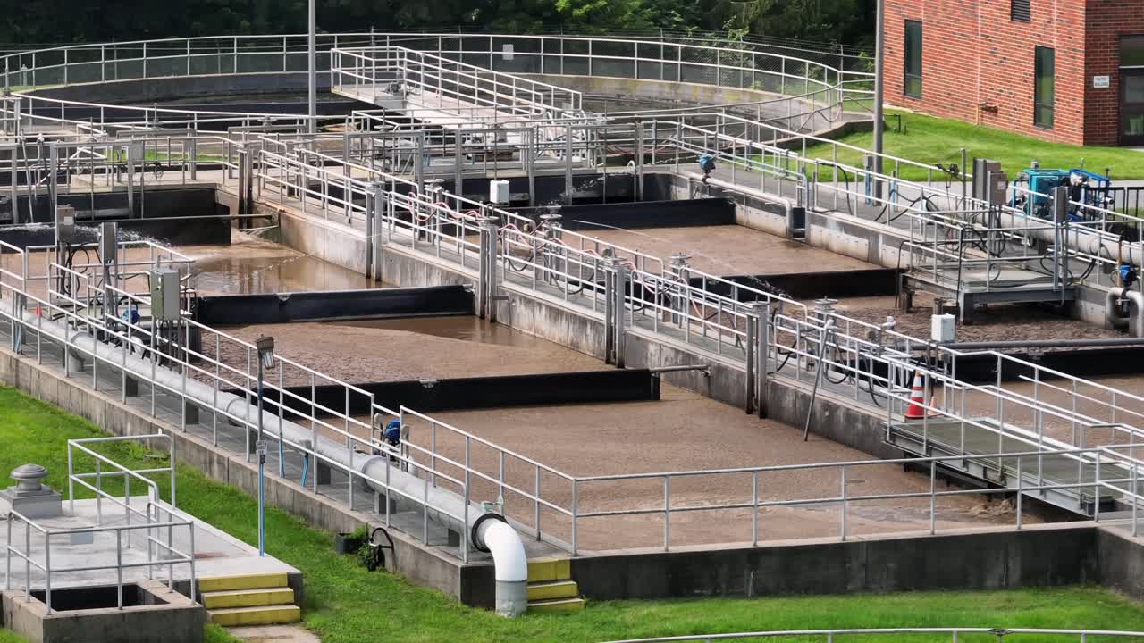 Sewage plant and wastewater treatment in America. Sunny day in suburb of town. Sedimentation tanks and pool filtering dirt. Aerial view
