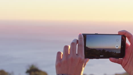 Nahaufnahme-Einer-Muslimischen-Frau,-Die-Mit-Dem-Smartphone-Ein-Foto-Macht,-Das-Wunderschöne-Meer-Bei-Sonnenuntergang-Fotografiert-Und-Den-Reise-Lifestyle-Beim-Sightseeing-Im-Urlaub-Genießt